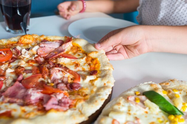 Le mani dei bambini con un primo piano della pizza sul tavolo