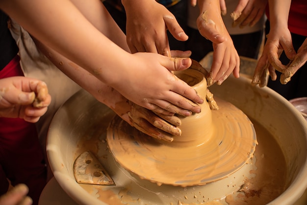 Children's hands work with clay on a special machine. Products from clay