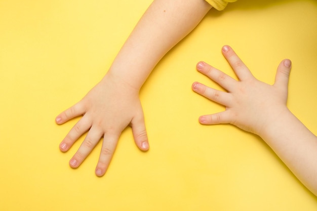 Le mani dei bambini su uno sfondo giallo con spazio per la copia