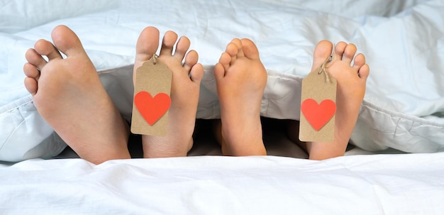 Photo children's heels lie on the bed under the covers with a tag on the finger, with a heart. st. valentine's day.