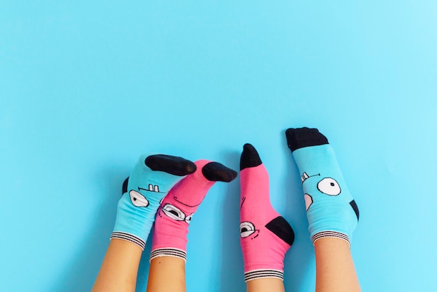 Photo children's legs in funny socks raised up on a blue background, feet having fun, creative concept