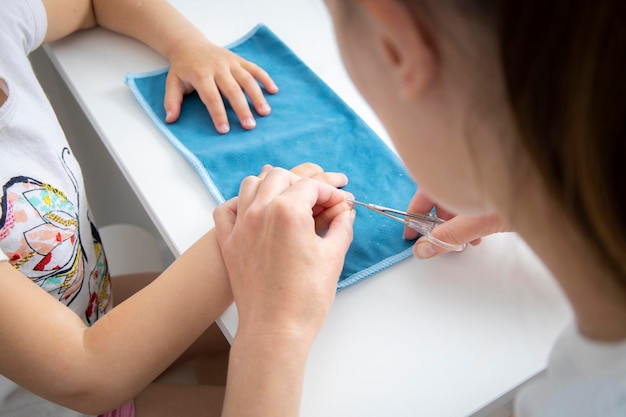 Children's manicure Mom cuts off her daughter's nails with nail scissors at home