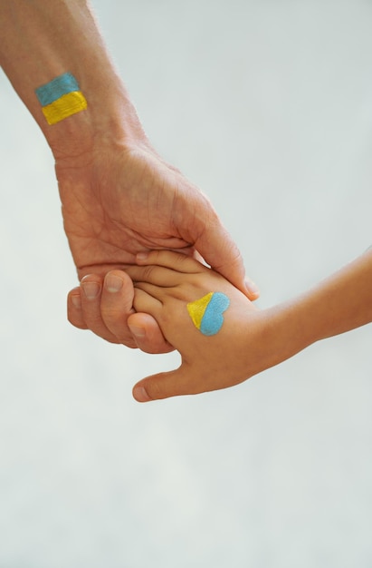 Children's and men's hands are painted in the colors of the yellowblue flag of Ukraine