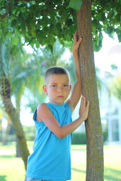 子供男性の夏のファッション 夏服を着たかわいい白人の男の子が公園でポーズをとる Tシャツを着た少年モデル