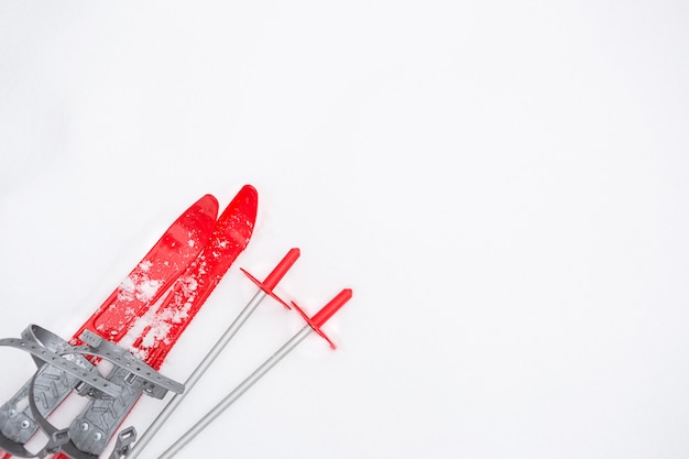 Children's red skis with sticks -layout in the snow. winter sport