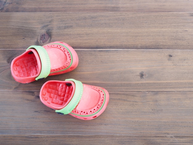 Children's rubber sandals on wooden background