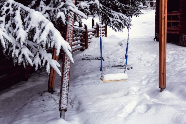 Children's swing in the yard covered with snow