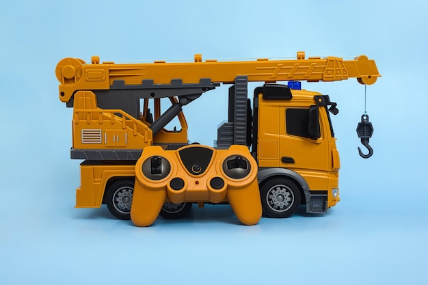 Children's toy radiocontrolled car crane with a remote control on a blue background