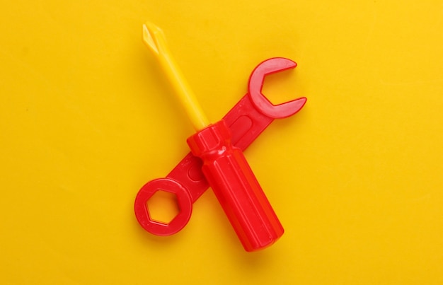 Children's toy tool. Wrench, screwdriver on yellow.