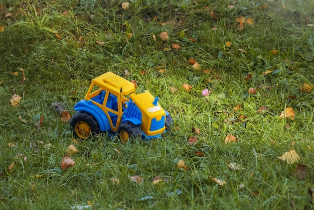 Children's toy yellow car forgotten on green grass