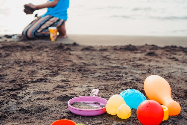 Foto giocattoli per bambini sdraiati sulla spiaggia. giocattoli di plastica sulla sabbia con uno sfondo di bambini che giocano o