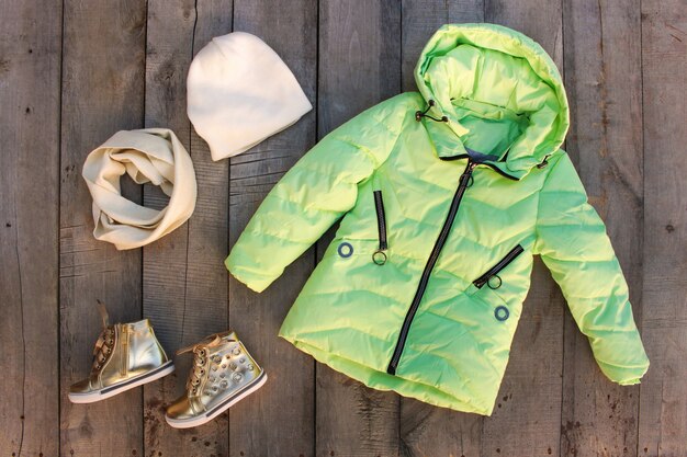 Children's winter clothes on old wooden table. Top view. Flat lay.