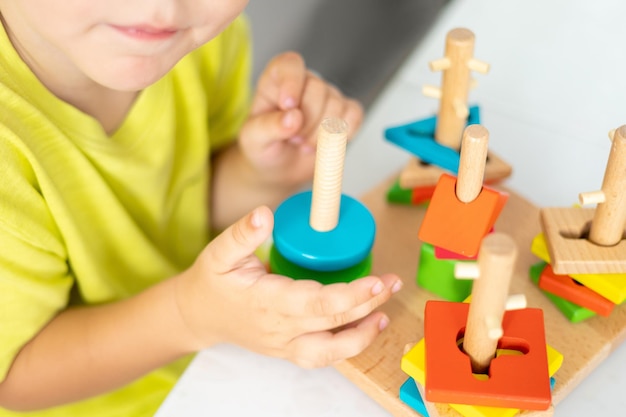 Foto giocattolo in legno per bambini il bambino raccoglie un giocattolo logico in legno giocattoli logici educativi per bambini primo piano delle mani dei bambini giochi montessori per lo sviluppo dei bambini sviluppo precoce