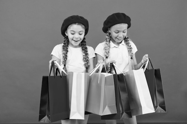 Children satisfied by shopping red background Obsessed with shopping and clothing malls Shopaholic concept Shopping become fun with best friends Kids cute schoolgirls hold bunch shopping bags