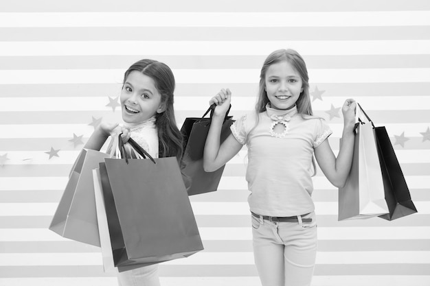 Children satisfied shopping striped background Obsessed with shopping and clothing malls Discount concept Kids cute girls hold shopping bags Shopping discount season Spending great time together