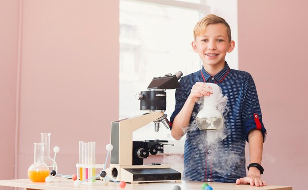 Photo children and science. happy boy conducting experiments with liquid nitrogen in laboratory with reagents, test tubes and flasks. early development, innovation, integrated education