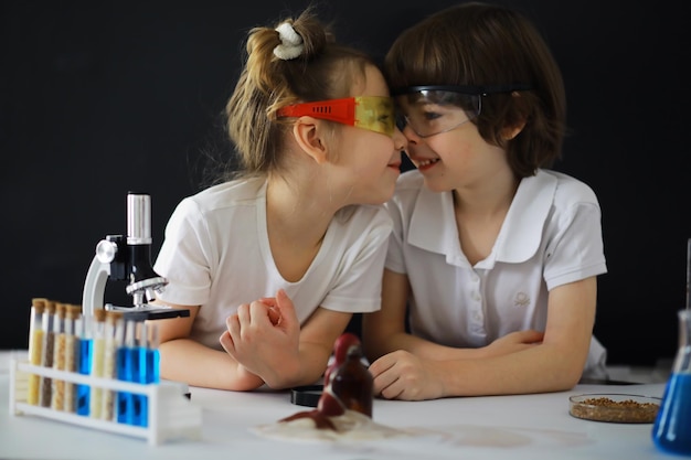 Children scientists Schoolchildren in the laboratory conduct experiments Boy and girl experiments with a microscope