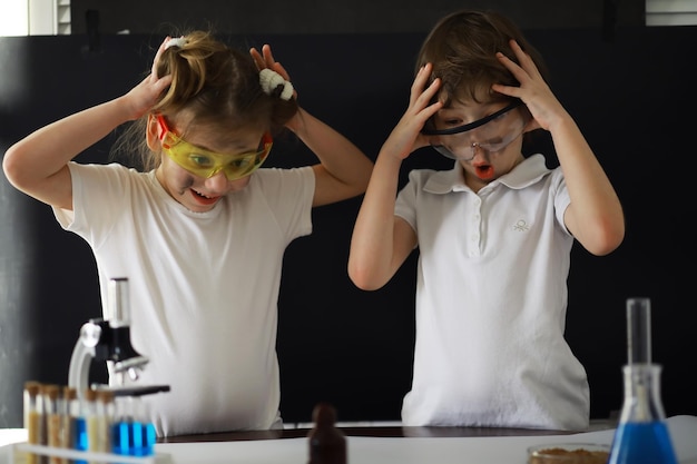 Bambini scienziati gli scolari in laboratorio conducono esperimenti ragazzo e ragazza esperimenti con un microscopio