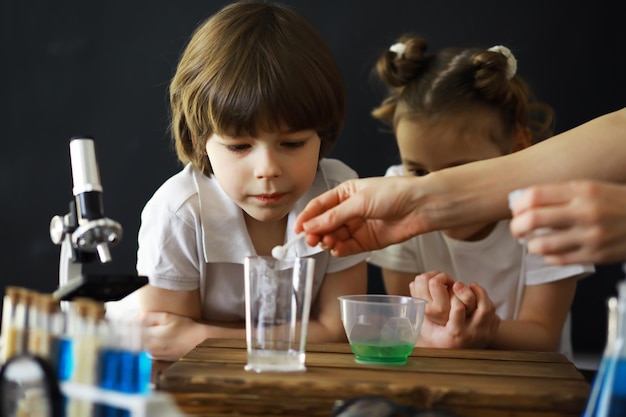 어린이 과학자 실험실의 학생들이 실험을 수행합니다. 소년과 소녀는 현미경으로 실험합니다.