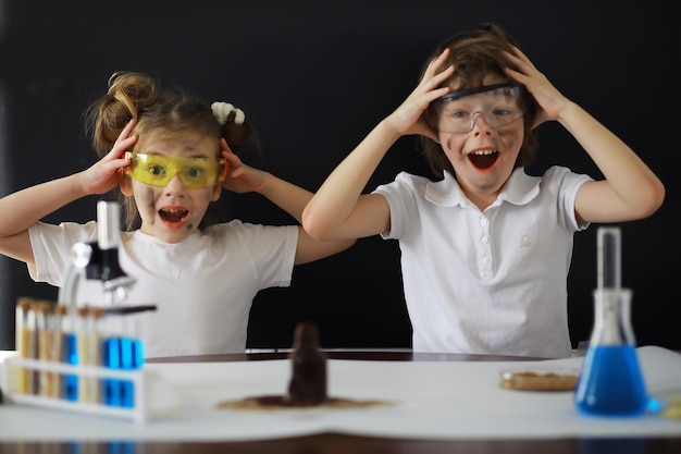 Photo children scientists schoolchildren in the laboratory conduct experiments boy and girl experiments with a microscope