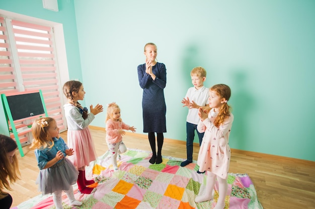 Photo children sing a song with a teacher together kids in a nursery teacher playing the active game with her preschool pupils