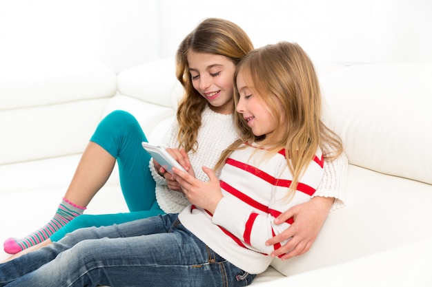 Gli amici della sorella dei bambini scherzano le ragazze che giocano insieme al pc della compressa