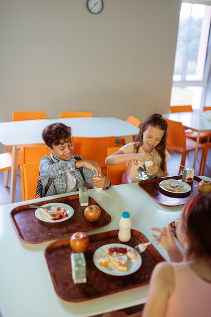 Фото Дети сидят за столом с подносами с едой во время обеда