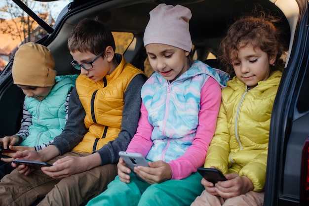 スマートフォンで車のトラックに座っている子供たち