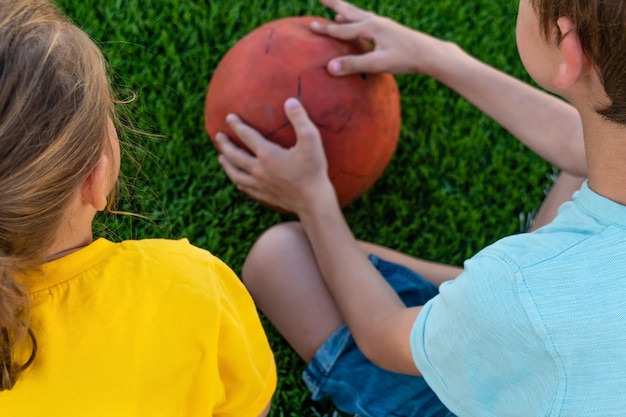 children sitting on green grass and holding ball