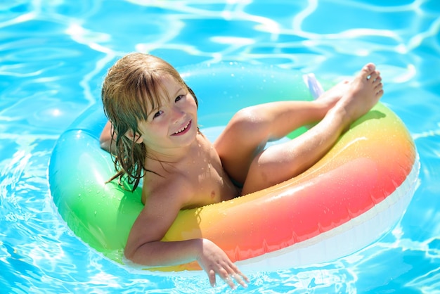 수영장 여름 방학에 풍선 링에 앉아 있는 아이들은 파란색에서 노는 재미있는 어린 아이입니다.