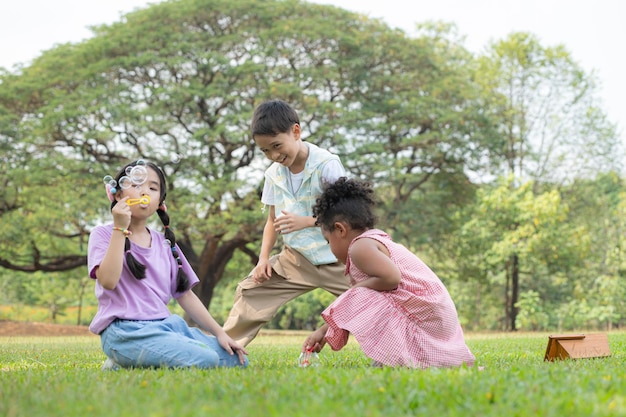 Children sitting in the park with blowing air bubble Surrounded by greenery and nature