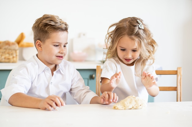 Children smiling while preparing the cake dough at home