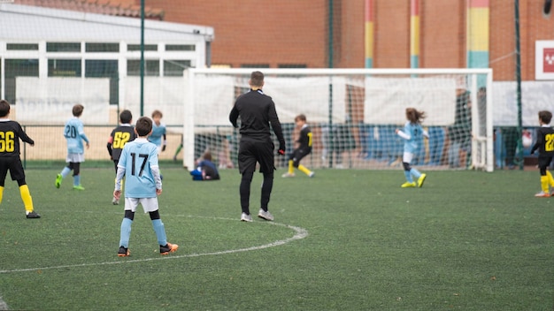 Foto partita di campionato della squadra di calcio per bambini l'attacco e l'azione difensiva si muovono mentre l'arbitro guarda con attenzione