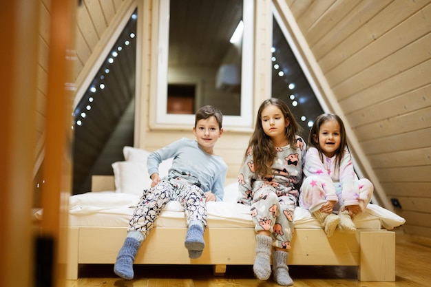 Children in soft warm pajamas playing at wooden cabin home Concept of childhood leisure activity happiness Brother and sisters having fun and playing together