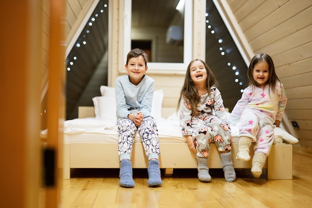 Children in soft warm pajamas playing at wooden cabin home Concept of childhood leisure activity happiness Brother and sisters having fun and playing together