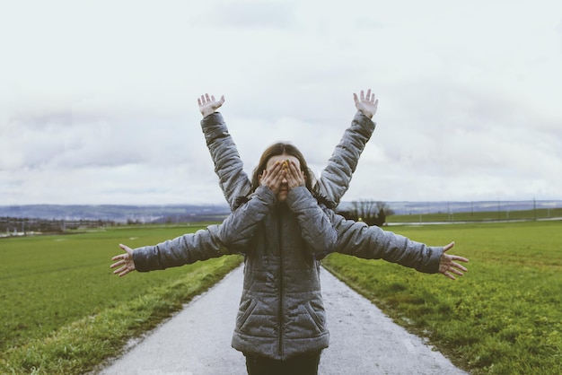 Children standing with arms outstretched on field against sky