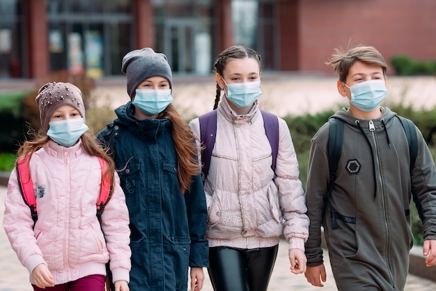 Children students in medical masks leave the school.