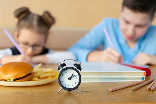 写真 学校で男の子と女の子の昼休みを勉強している子供たちファーストフードの子供たちの不健康な食事