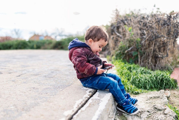 携帯電話で屋外でインターネットをサーフィンする子供たち