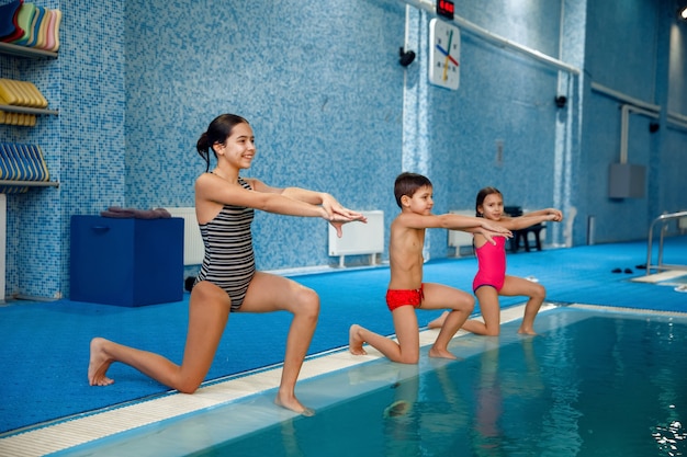 Children swimming group, workout at the poolside.