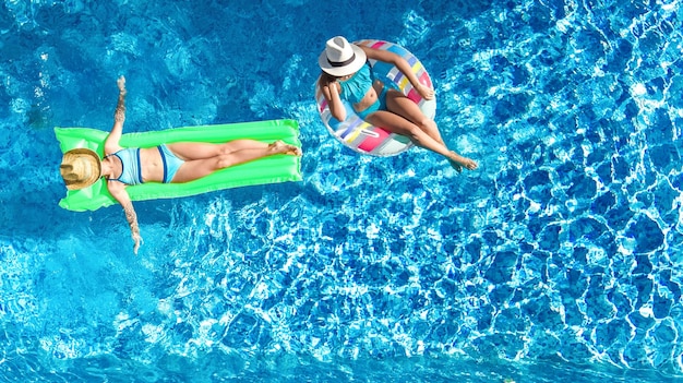 Children in swimming pool aerial drone view from above happy kids swim on inflatable ring donut