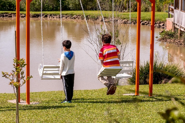 湖の前の庭でブランコに乗る子供たち