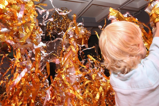 children throw sliced golden paper at each other paper show