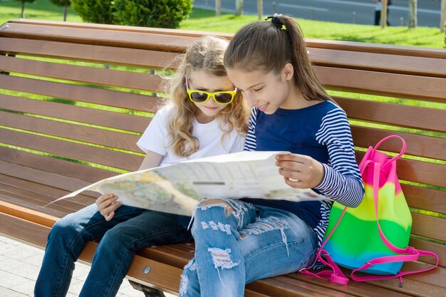 Children tourists with map of city on the bench