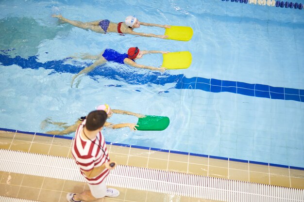 Bambini che si allenano con l'allenatore in piscina