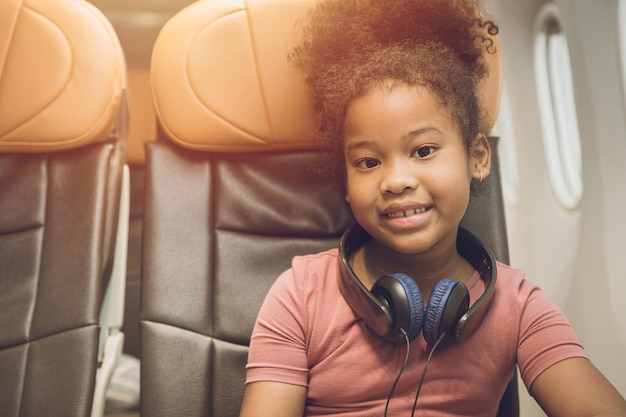 Children traveling alone or unaccompanied minor child girl fly travel sitting alone in flight cabin seat happy smile