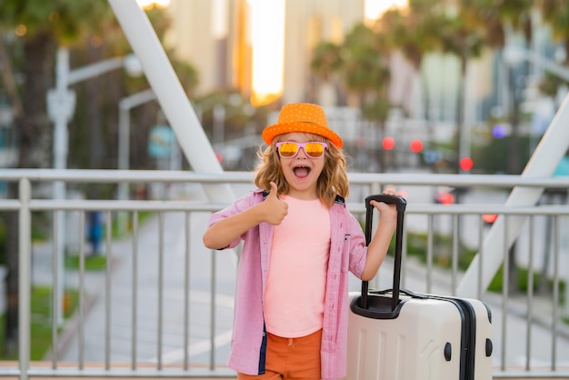 旅行の子供たち旅行の街の通りの夢に屋外のスーツケースを運ぶ幸せな子供