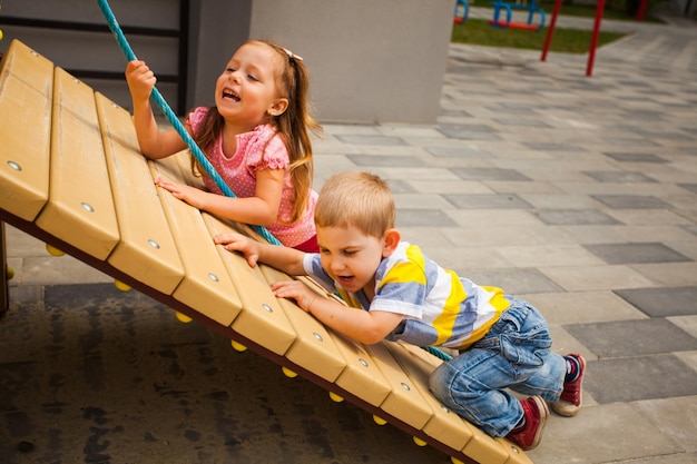 Children trying climbing the rope on playground outdoors