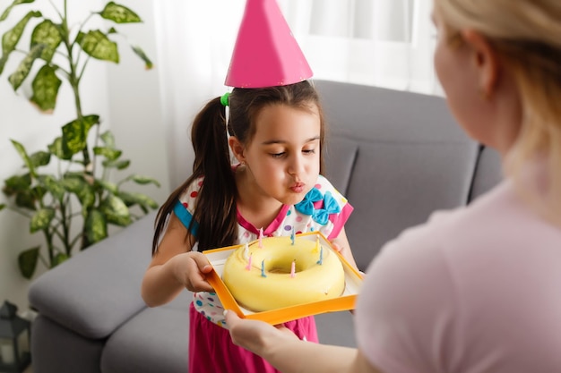 Children virtual birthday party with cake online together with her friend in video conference. With digital telephone for a online meeting. Girl celebrating birthday online in quarantine time