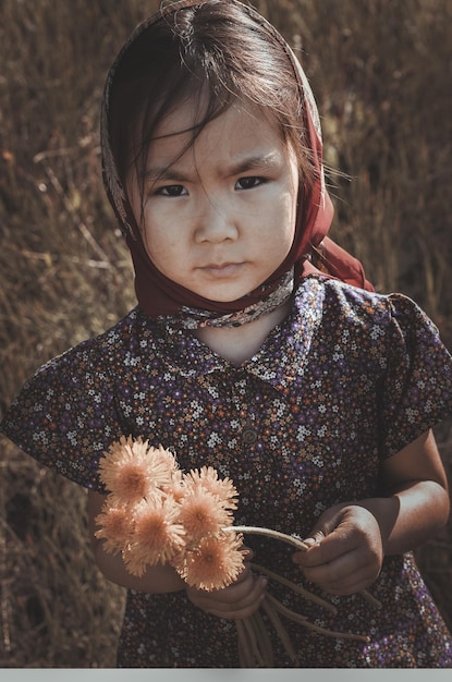 children and war, a little asian village girl in a field with flowers